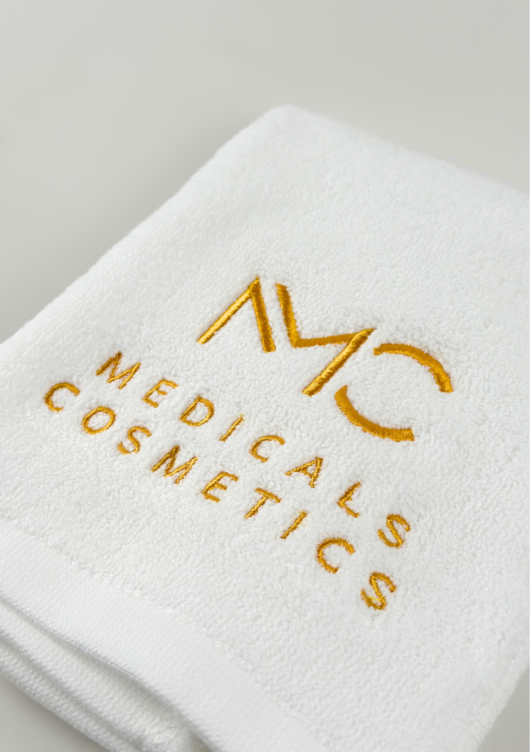 TOWEL MEDICALS COSMETICS SMALL WHITE, GOLDEN LOGO 
Kis pamut törölköző Medicals Cosmetics fehér arany hímzéssel