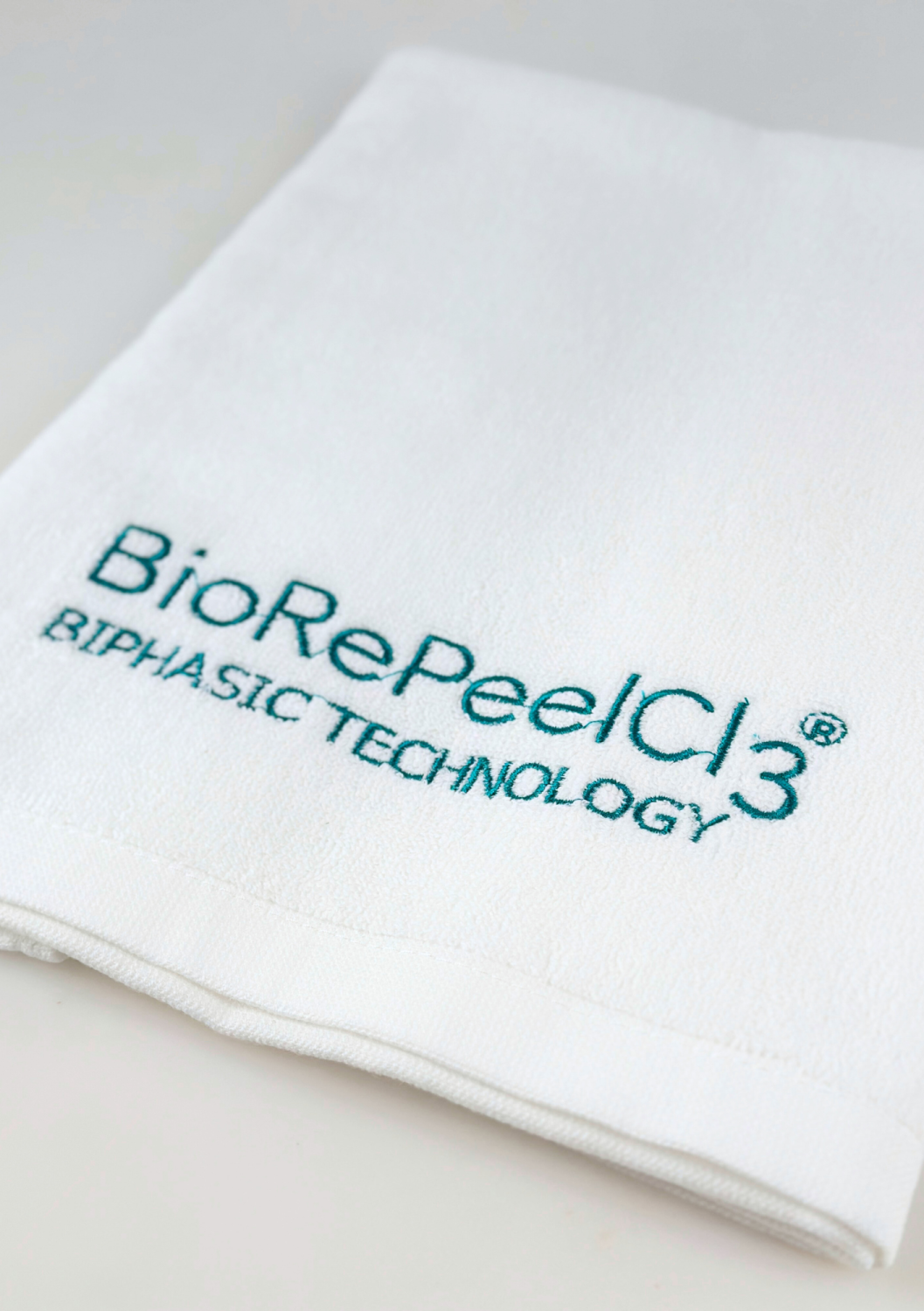 TOWEL BIOREPEEL SMALL, WHITE WITH BLUE-TO-GREEN LOGO 
40x60 cm BioRePeel logóval ellátott kis pamut törölköző, fehér türkiz hímzéssel