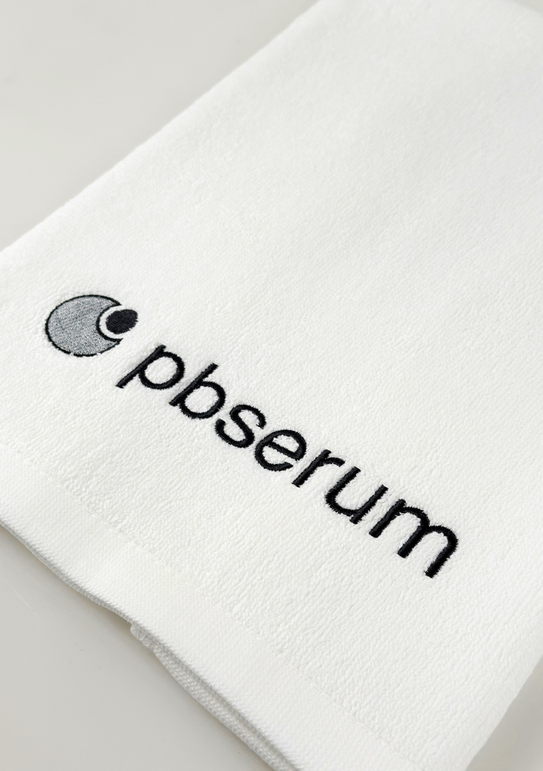 TOWEL PBSERUM SMALL, WHITE WITH GREY LOGO 
40x60 cm PBSerum logóval ellátott kis pamut törölköző, fehér szürke hímzéssel